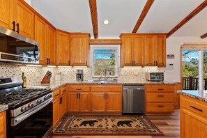 A kitchen with wooden cabinets, a stainless steel stove, and a dishwasher. - Located in the Castle Glen Estates! Recently Remodeled Master! Pet Friendly! Pool Table! Foosball! (Big Bear Lake)