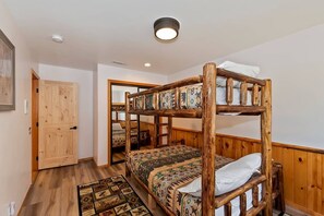 A bunk bed room with a wooden headboard, a patterned bedspread, and a wooden floor. - Located in the Castle Glen Estates! Recently Remodeled Master! Pet Friendly! Pool Table! Foosball! (Big Bear Lake)