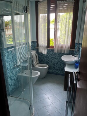 A bathroom with a glass shower enclosure, a toilet, a sink, and a window with curtains. - Villa with garden a few steps from the sea and the Versiliana park (Marina di Pietrasanta)