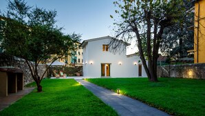 A modern house with a well-maintained lawn, a paved pathway leading to the entrance, and a stone wall on one side. - The City Oasis in Lucca (Lucca)
