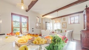 A spacious dining area with a marble table set for a meal, featuring a variety of fruits and vegetables. - Amore Farmhouse Retreat (Lucca)