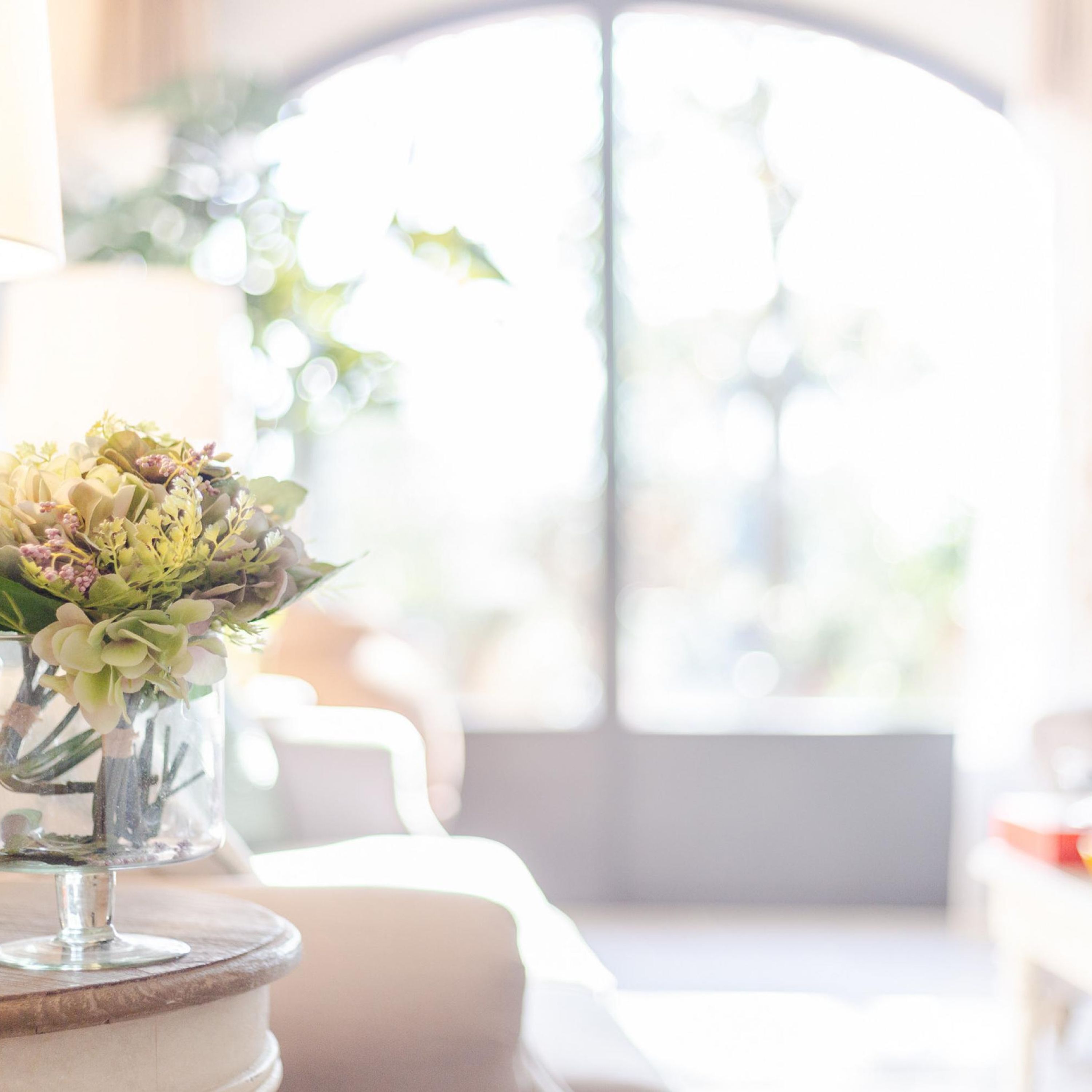 A clear view of a room with a large window, a table with a vase of flowers, and a chair.