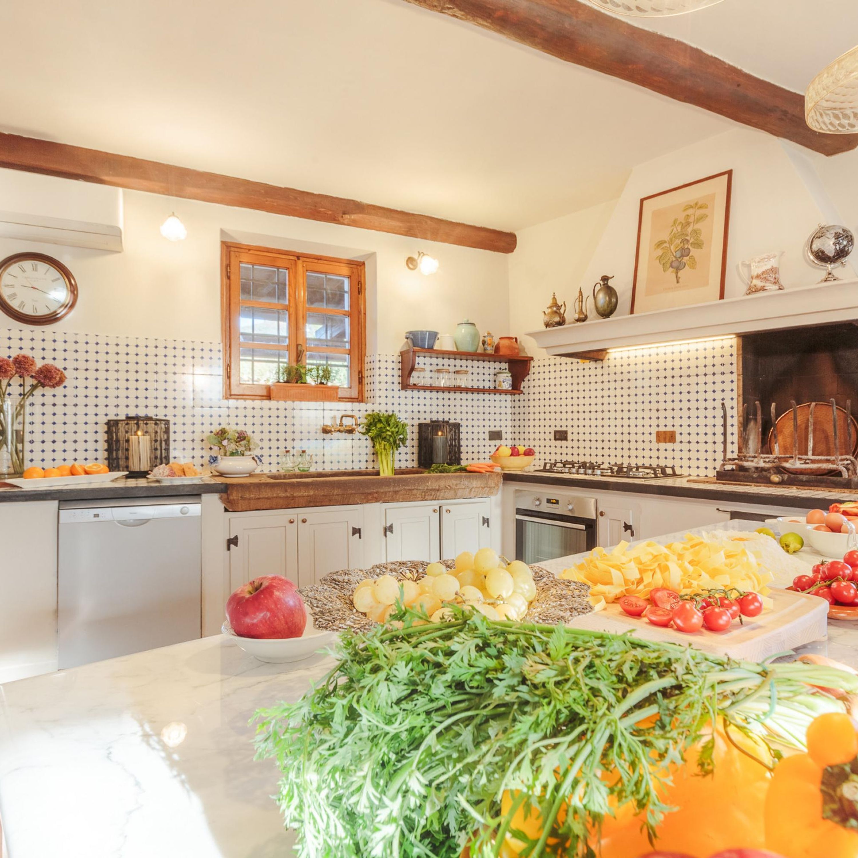 A kitchen with white cabinets, a wooden countertop, and a variety of fruits and vegetables displayed.