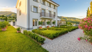 A two-story building with a balcony, surrounded by well-maintained gardens and a gravel path. - Villa Asti in Segromigno in Monte (Capannori)