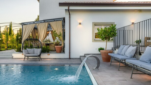 A swimming pool with a water feature, outdoor seating, and potted plants. - Villa Asti in Segromigno in Monte (Capannori)
