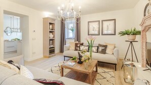 A modern living room with a chandelier, a sofa set, a coffee table with decorative items, and a bookshelf. - Villa Asti in Segromigno in Monte (Capannori)