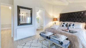 A modern bedroom with a large bed, a bench, a mirror, and a bedside table. - Villa Asti in Segromigno in Monte (Capannori)