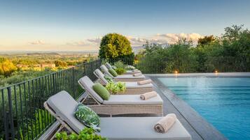 Un área junto a la piscina con sillones de mimbre, una piscina y vistas al paisaje.
