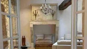 Un amplio salón con suelo de baldosas de piedra, chimenea y candelabro.