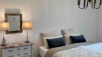 Un dormitorio con cama, cómoda, espejo y candelabro.