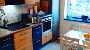 A modern kitchen with wooden cabinets, a built-in oven, and a window with a view of the outdoors. - Schöne und Ruhige Ferienwohnung in Ottendorf (Sebnitz)