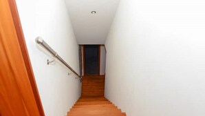 A narrow staircase with wooden steps and a metal handrail, leading to a dark doorway at the top. - The Mountains are Calling Retreat (Quarten)