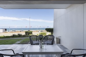 A patio with two wicker chairs, a table, and a vase with flowers. - Sea Spray AG04 (Cape Town)