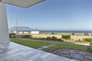 A patio with a view of the ocean and a distant mountain. - Sea Spray AG04 (Cape Town)