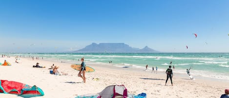 A beach with people, kites, and surfboards.