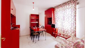 A compact living space with a kitchenette, dining area, and a sofa.