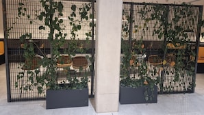 A modern interior with two black metal partitions, each with a planter box containing green plants. - Captivating 1-bed Apartment in Manchester (Manchester)