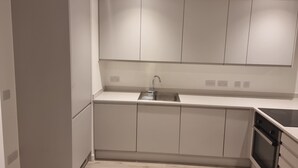 A modern kitchen with white cabinets, a stainless steel sink, and a built-in oven. - Captivating 1-bed Apartment in Manchester (Manchester)