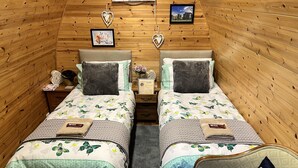 A cozy room with two beds, wooden walls, a small table, and a chair. - Beautiful Twin Glamping Pod in Salisbury (Salisbury)