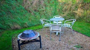 A patio area with a round table and four chairs, surrounded by gravel and greenery. - Beautiful Twin Glamping Pod in Salisbury (Salisbury)
