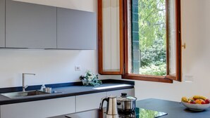 Cocina moderna con una isla grande, electrodomésticos integrados y una ventana que ofrece vistas a zonas verdes.