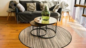 Un salon avec un canapé, deux fauteuils, une table basse et un tapis.
