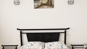 Un lit recouvert d’une couvre-lit à motifs floraux, deux tables de chevet et un tableau accroché au mur.