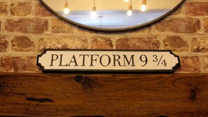 Eine Ziegelwand mit einem Holzpaneel und einem Schild, auf dem 'PLATFORM 9 3/4' steht.