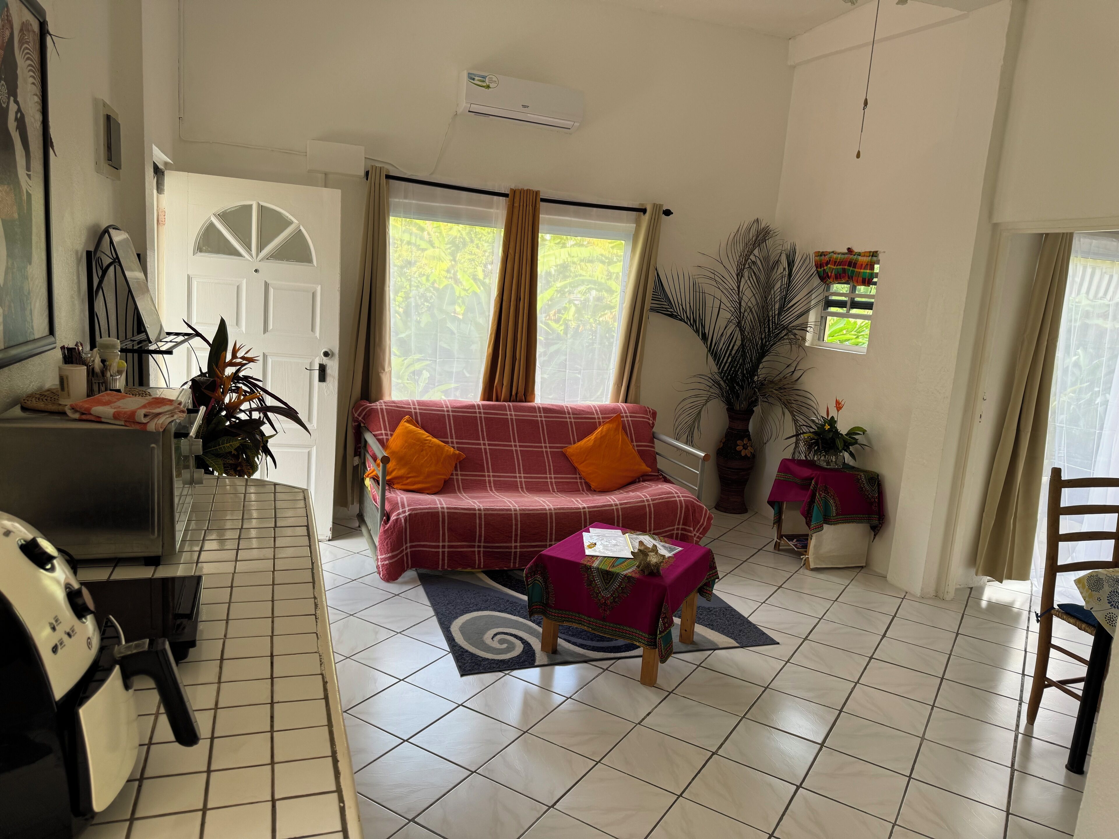 Un salon avec un canapé, une petite table, une machine à café et une plante en pot.