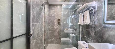 Un baño moderno con cabina de ducha de vidrio, inodoro blanco y lavamanos grande.