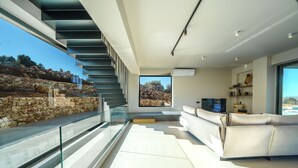 A modern living room with a glass railing, a sofa, and a television.