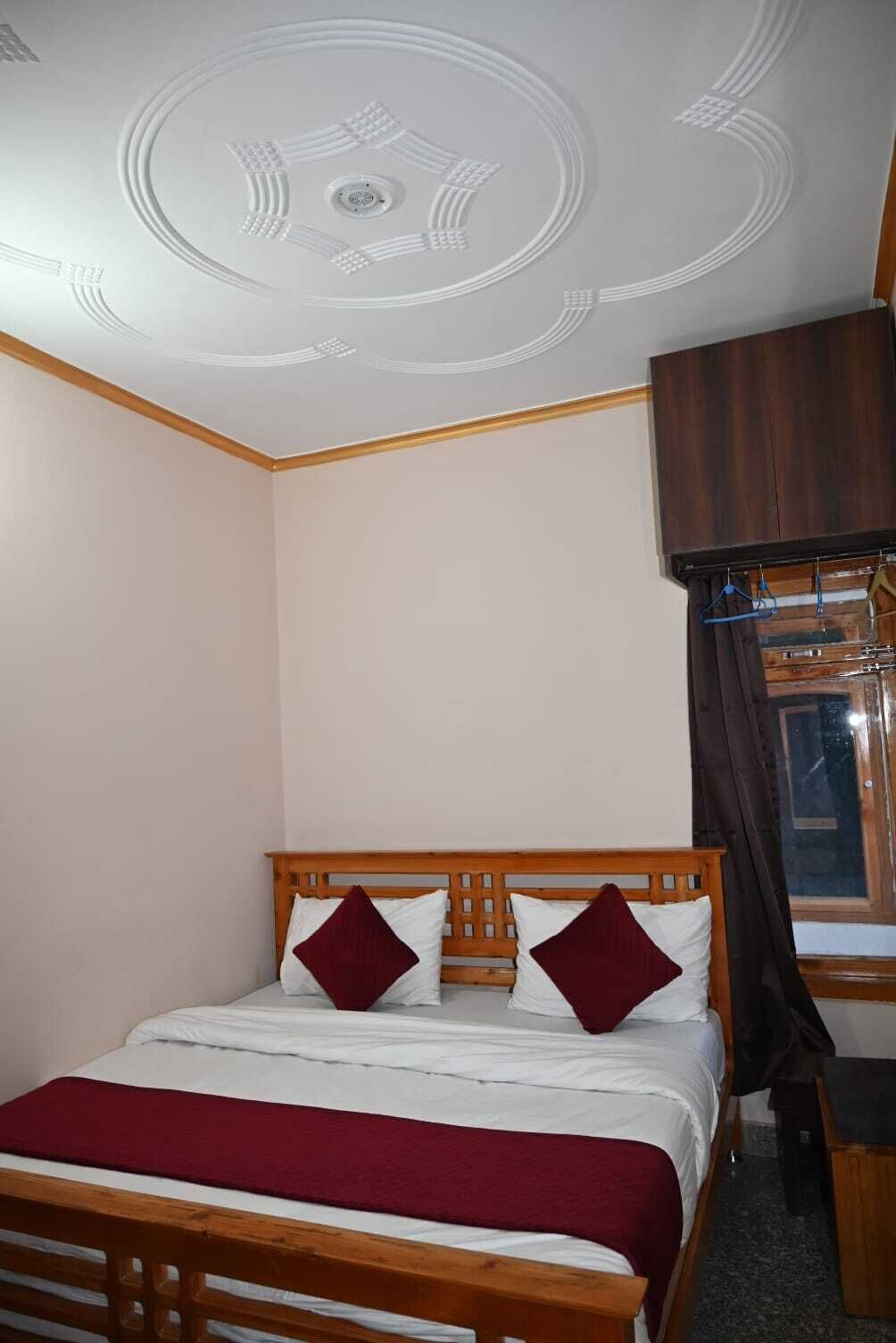 Un dormitorio con una cama de madera, una colcha roja y blanca y un techo con diseño circular.