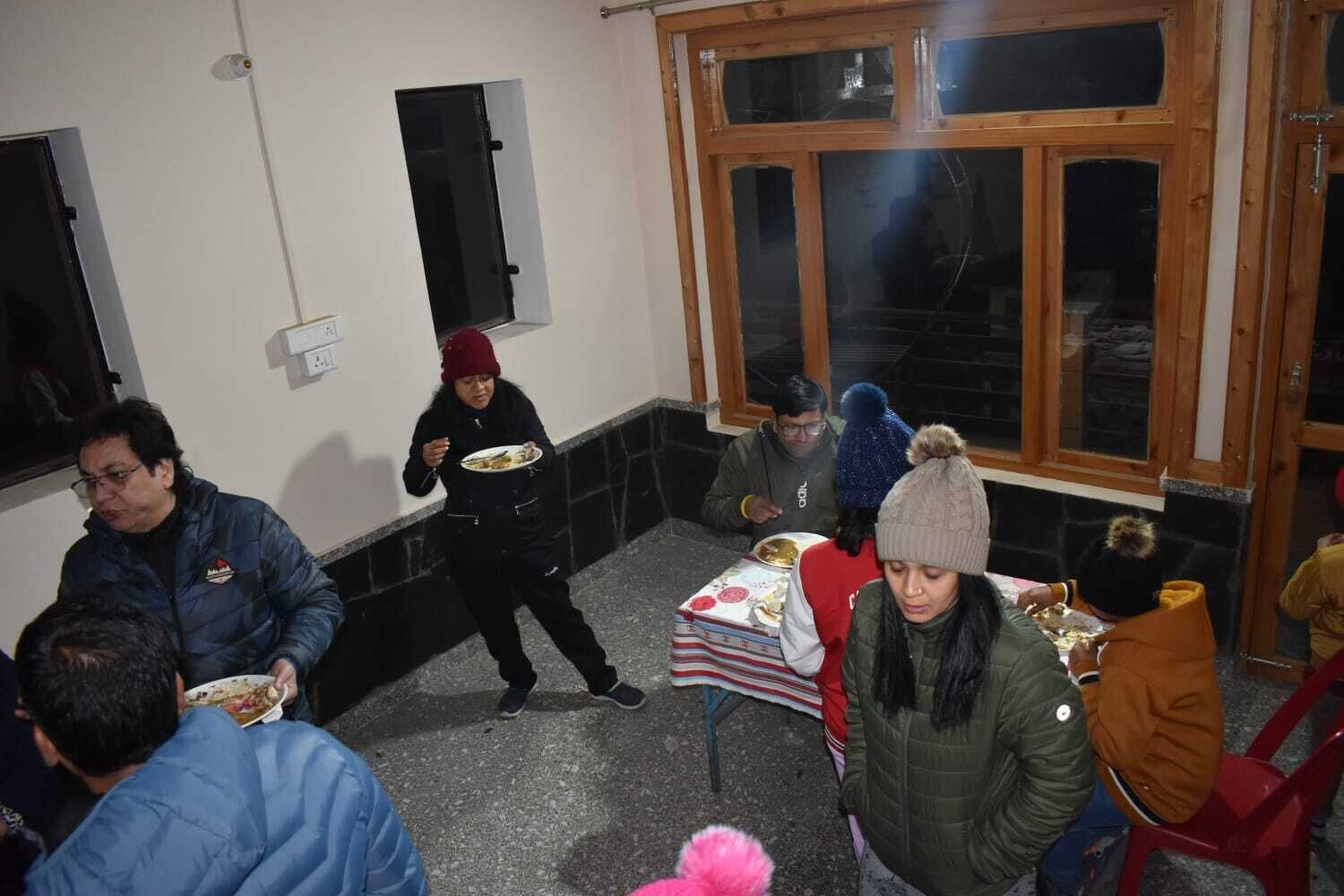 A group of people dining in a room with a large window and a door.