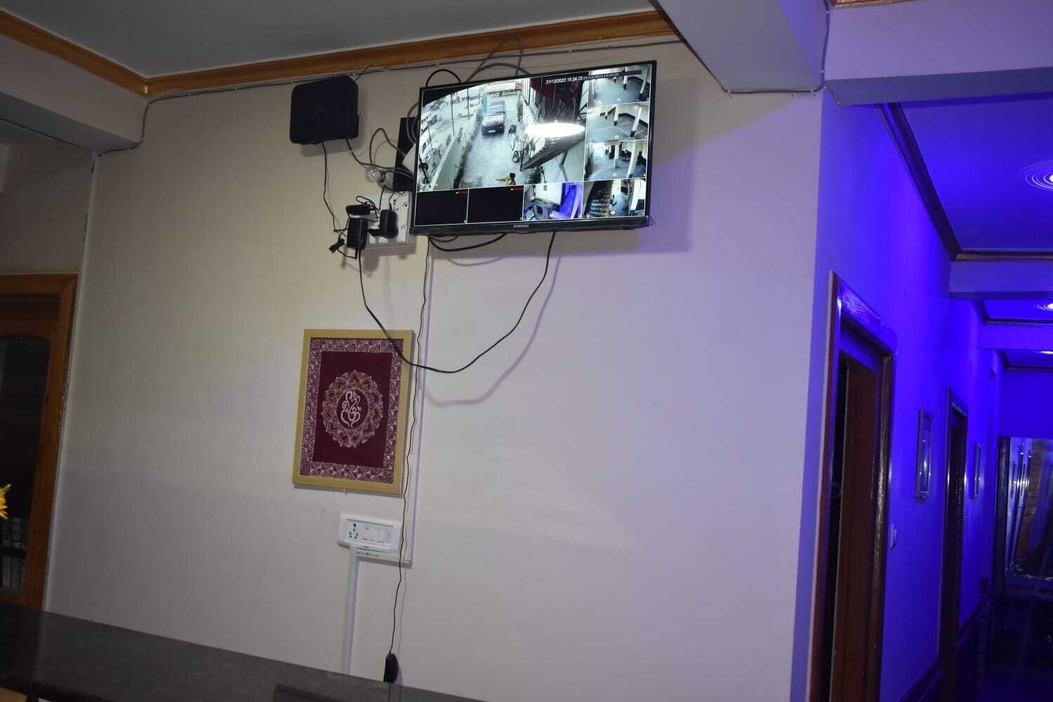 Sistema de cámaras de seguridad instalado en una pared, con un enchufe y un adorno debajo.