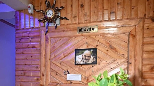 A reception area with a wooden wall, a clock, a framed photo, a sign reading "RECEPTION", and a potted plant. - Hotel Lohaghat Regency  (Lohaghat)