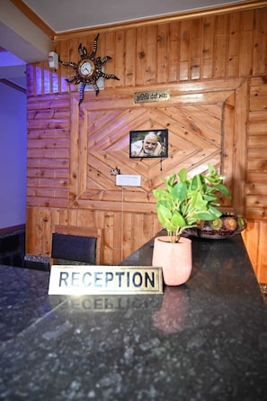 Un área de recepción con una pared de madera, un reloj, una foto enmarcada, un letrero que dice 