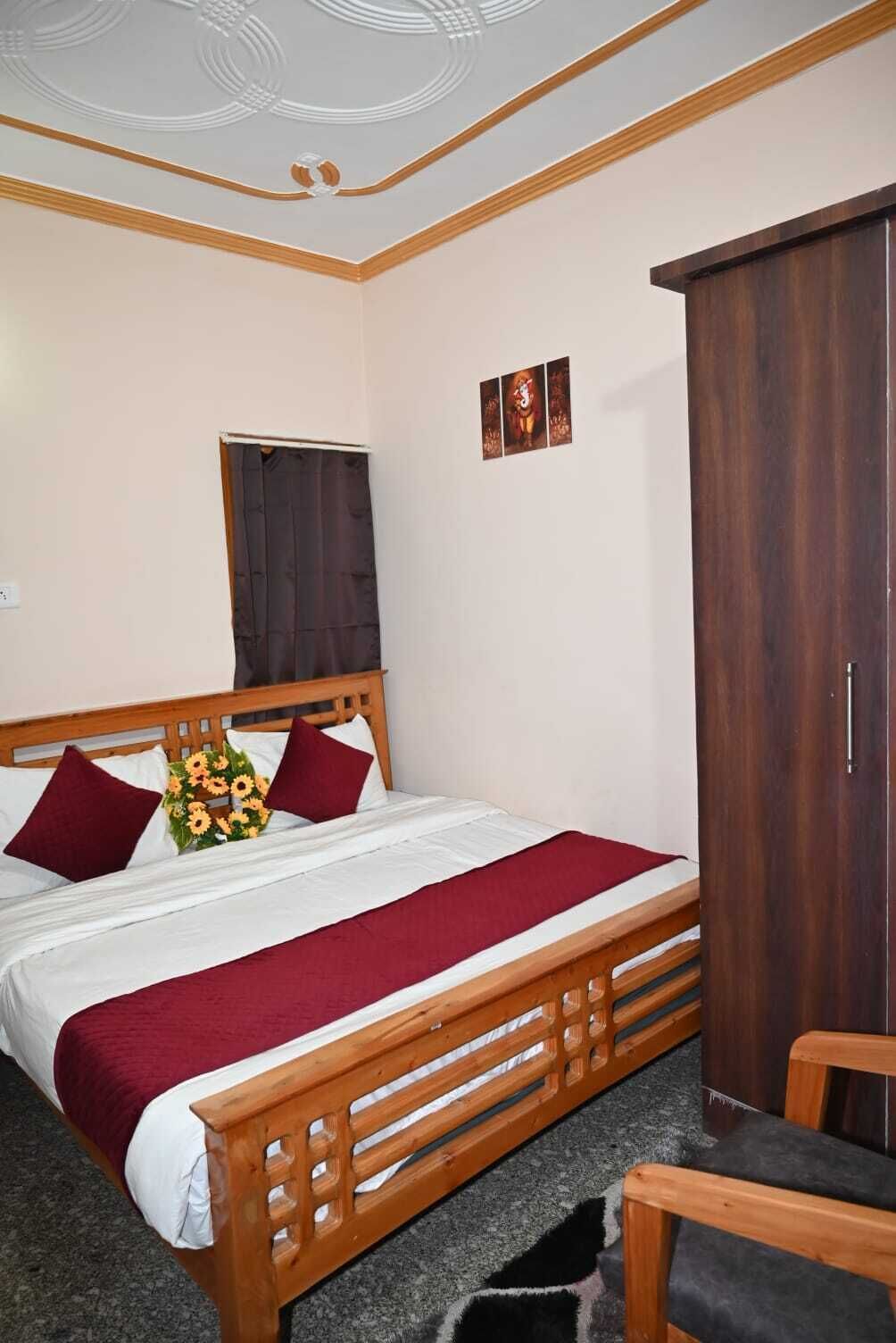 Una cama bien hecha con tablero de madera, un armario de madera oscura y una pequeña silla de madera.