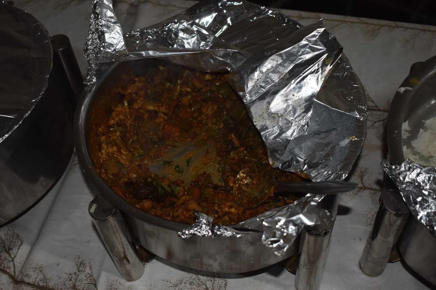 Una olla grande con comida cubierta con papel de aluminio sobre una estufa.