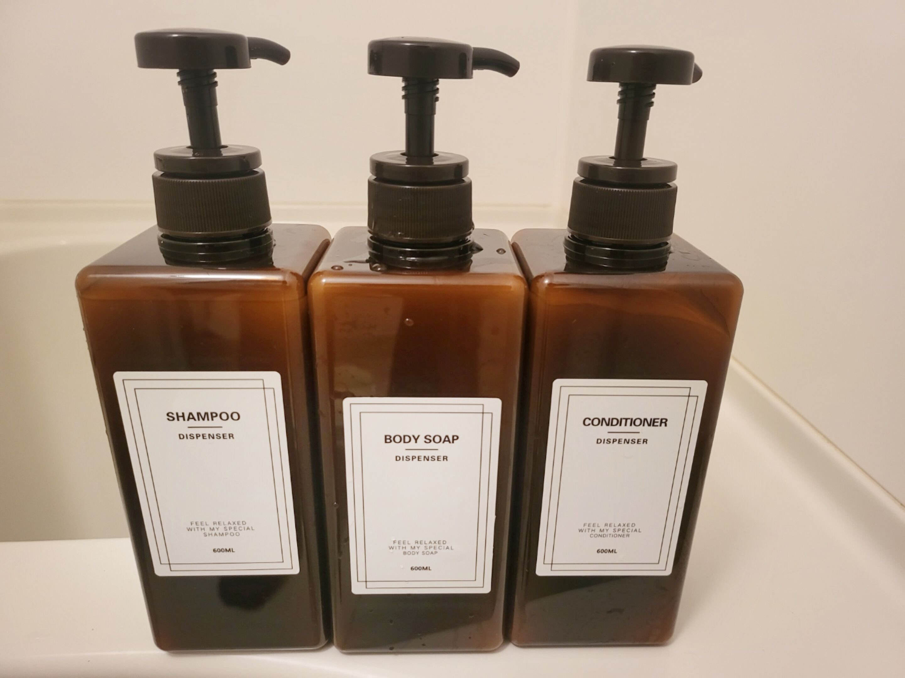 Three bottles of liquid soap, each with a pump dispenser, labeled as shampoo, body soap, and conditioner.
