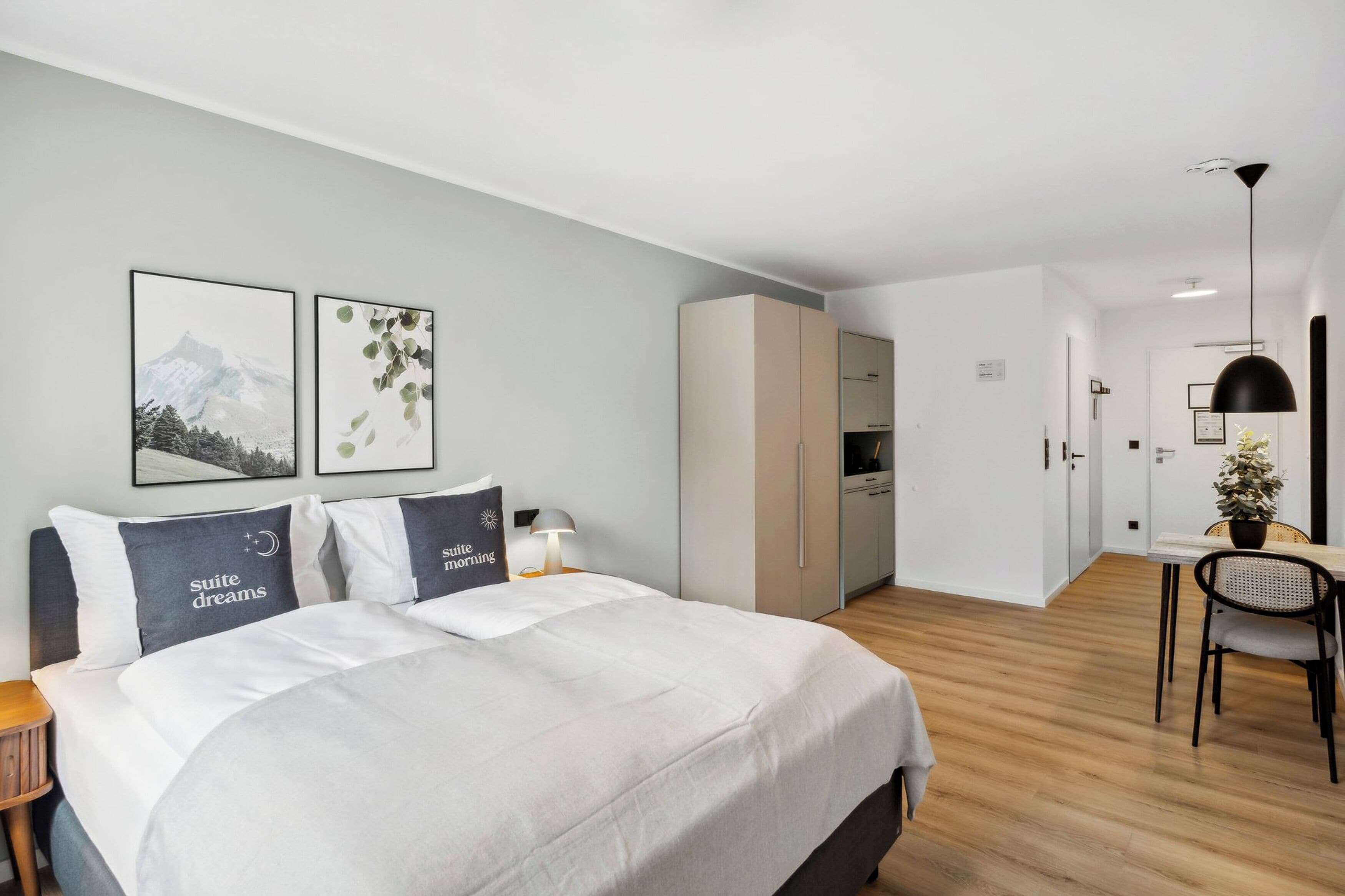 Ein modernes Hotelzimmer mit einem Bett, Nachttischen, einem Schreibtisch und einem Sessel.