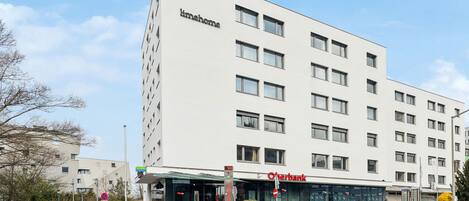 Een modern gebouw met een platte gevel, meerdere ramen en een bord met 'timehome' en 'Overbank' erop.