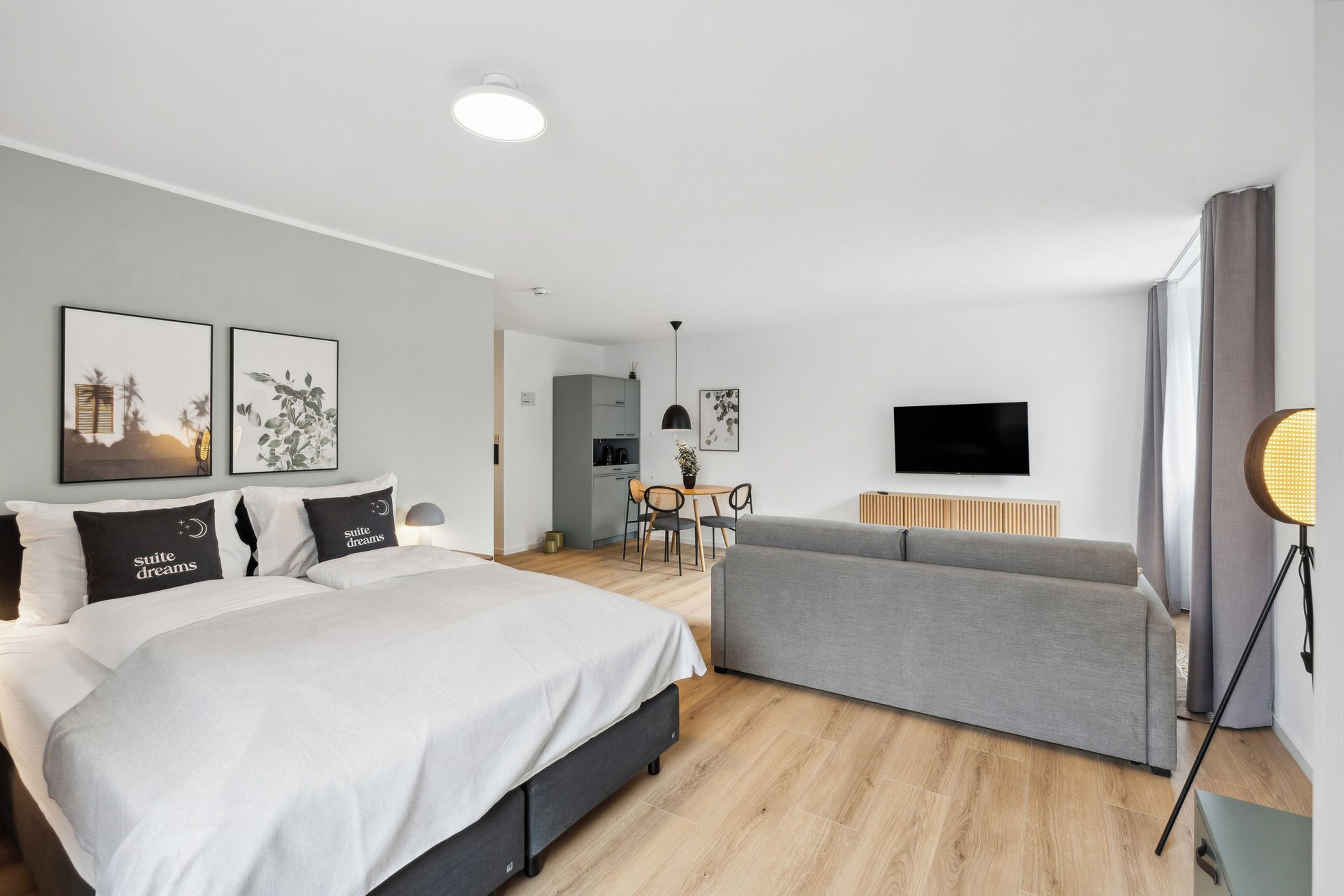 Une chambre d’hôtel moderne équipée d’un lit, d’un canapé, d’une télévision et d’un coin repas.
