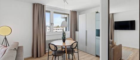 A modern room with a dining table, chairs, a sofa, a TV, and a large mirror.