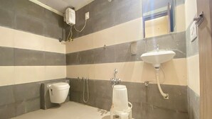 A bathroom with striped walls, a toilet, a sink, and a shower. - Hotel Kalyan Palace (Ahmedabad)