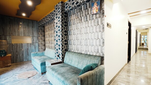 A modern living room with a sofa, a patterned wall, and a marble floor. - Hotel Versova Inn (Mumbai)