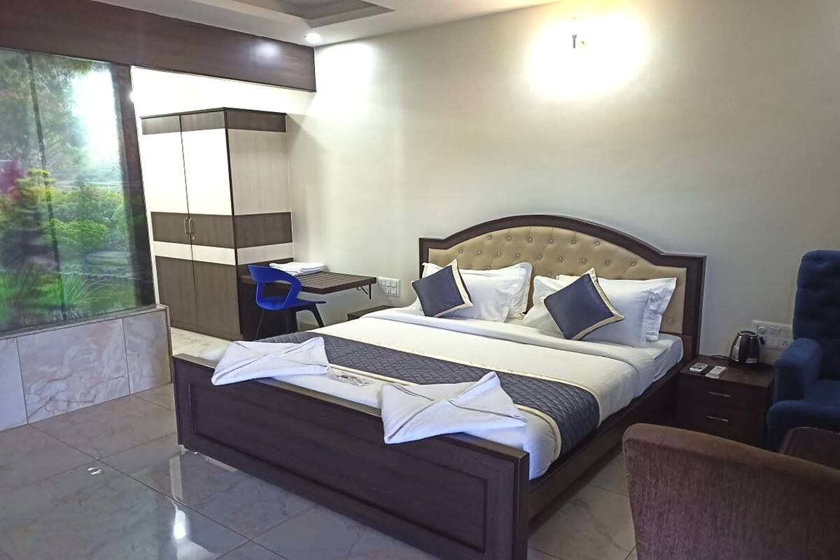 A modern hotel room with a large bed, a desk, and a wardrobe.