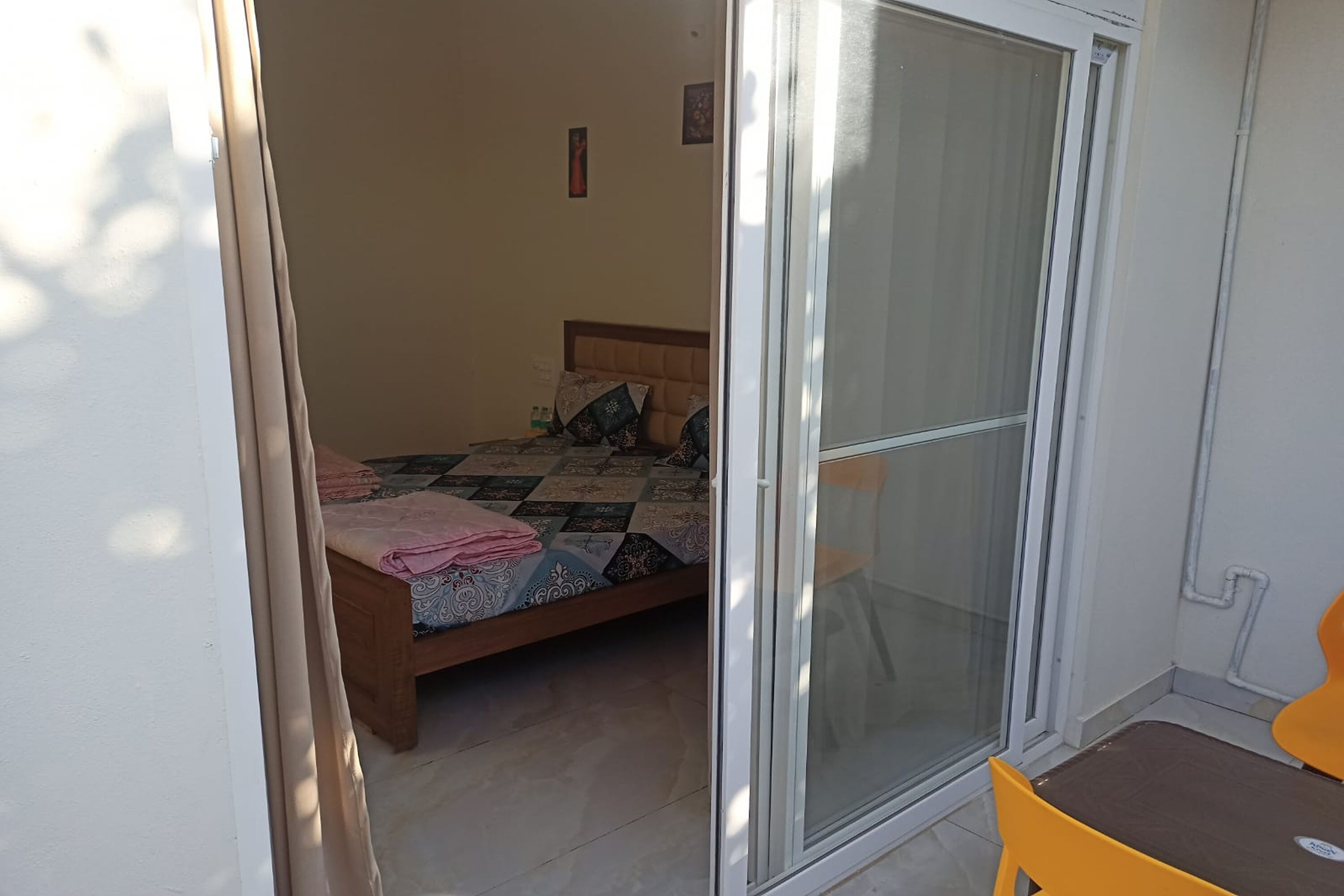 Een slaapkamer met een bed, een stoel en een schuifdeur.'