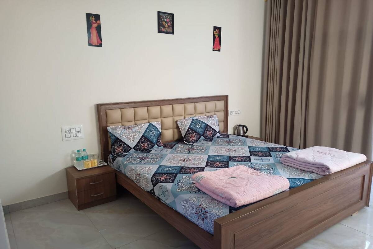 A neatly made bed with a patterned bedspread, a wooden headboard, and a bedside table with a tray of toiletries.
