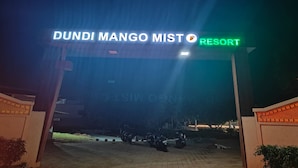 La entrada al Dundi Mango Mist Resort, con un letrero sobre el portón y motocicletas estacionadas al frente.