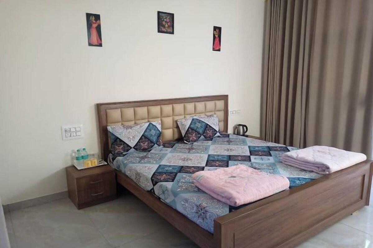 A bedroom with a bed, nightstand, and a wall with three pictures.